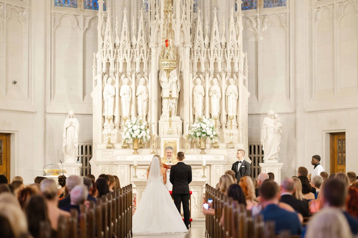 A couple celebrating their wedding before the carved stone reredos at Saint James Chapel