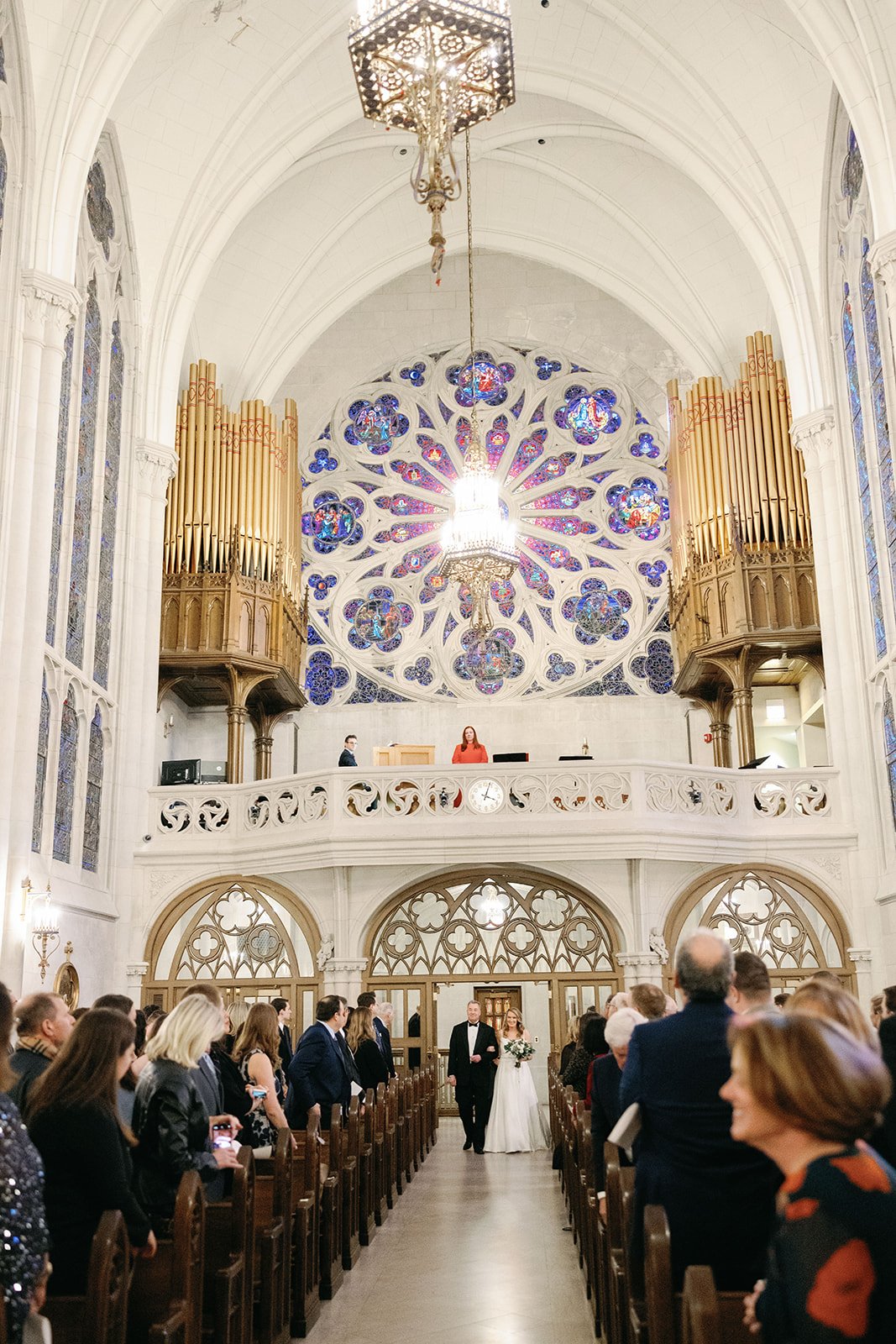The chapel’s organ pipes and rose window above a wedding procession